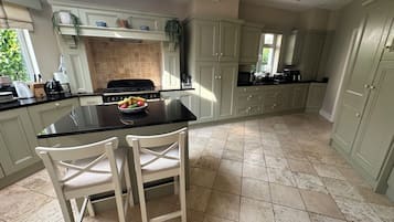 A kitchen with a central island, white chairs, a stove, and cabinets.
