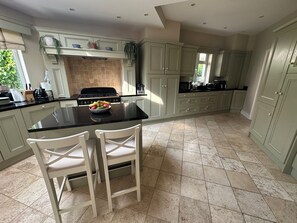 A kitchen with a central island, white chairs, a stove, and cabinets. - Elegant tranquil family home in Dublin – ideal base for exploring Ireland! (Dublin)