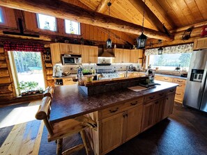 A rustic cabin-style kitchen with wooden cabinets, a granite countertop, and a large island.