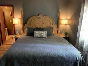 Ein Schlafzimmer mit einem großen Bett, einem hölzernen Kopfteil, zwei Nachttischlampen und einem Kissen mit dem Wort 'GRATEFUL'.