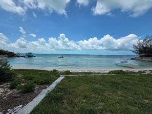 Ein Strand mit Booten, einem Steg und einer Rasenfläche.