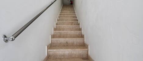 Una escalera con escalones de mármol y barandilla de metal.