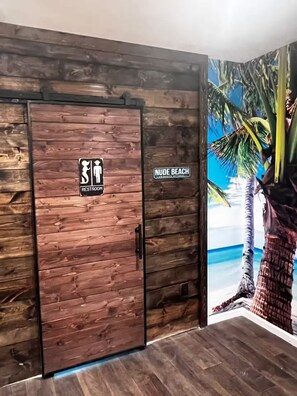 A wooden wall with a restroom sign and a 'NUDE BEACH' sign. - Tropical Beach Spa Studio, Jacuzzi, Kitchen, WiFi (Sparks)