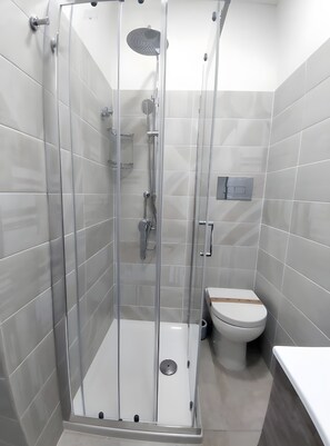 Un baño moderno con ducha de mampara de vidrio, inodoro y lavamanos.