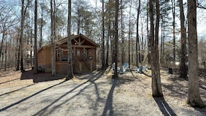 Eine Hütte im Wald mit einer Terrasse und Sitzgelegenheiten im Freien.