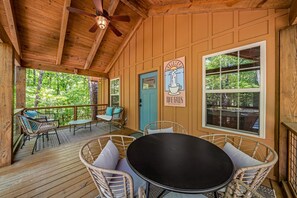 Eine Holzterrasse mit Korbmöbeln, einem Deckenventilator und einer Tür mit dem Schild 'Time Falls'.