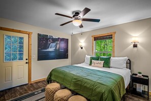 A bedroom with a bed, a ceiling fan, a window with a view, and a wall-mounted light. - Peaceful Woodland Cabin Near DeSoto State Park & Little River Canyon, Alabama (Mentone)