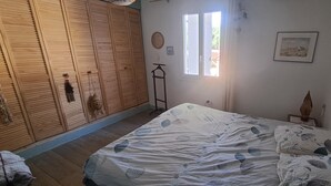 A bedroom with a bed, wooden wardrobe, a window, and a wall-mounted picture. - Cozy house with a garden and pool in Carpentras (Carpentras)