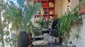 A covered patio area with potted plants, a wicker chair, and a wooden ceiling. - Cozy house with a garden and pool in Carpentras (Carpentras)