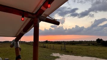 Un paisaje rural con un camino de grava, cerca de madera y una vista al atardecer.
