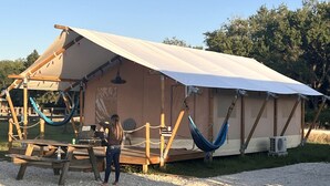 A tented accommodation with a wooden deck, a hammock, and a table.