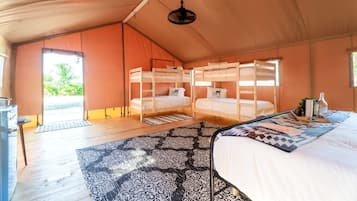 Alojamiento con carpa, camas literas, una lámpara colgante y vistas a la vegetación.