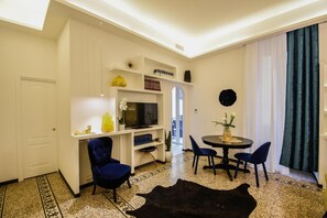 Ein modernes Wohnzimmer mit Fernseher, Sitzgelegenheiten und Essbereich.