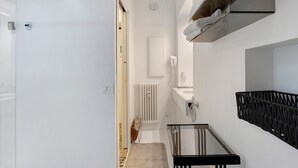 Un bany modern amb un espai de dutxa de vidre, un lavabo blanc i un porta tovalloles.