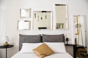 Ein Hotelzimmer mit einem Bett, zwei Nachttischen, einer Lampe und einem Spiegel.