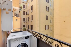 A compact balcony with a washing machine, a potted plant, and a metal railing. - Ellie Luxury Apartment with Balcony, Wi-Fi, and Air Conditioning (Rome)