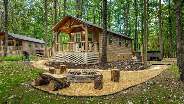 Une cabane dotée d’une terrasse, entourée d’une forêt.