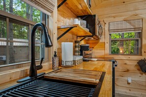 Ein Holzblockhaus-Innenraum mit Küchenbereich, einschließlich Spüle, Arbeitsplatte und verschiedenen Küchengeräten.