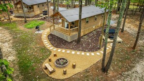 Une cabane dotée d’une terrasse, d’un foyer extérieur et d’un espace salon extérieur abrité.