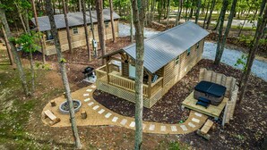 Une cabane dotée d’une terrasse, d’un foyer extérieur et d’un espace salon extérieur abrité.