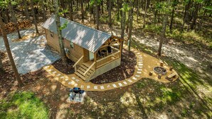 Une cabane en bois dotée d’une terrasse, entourée d’une forêt.