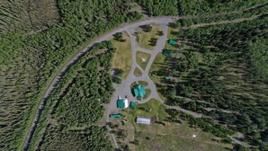 An aerial view of a property with a central building surrounded by forested areas and a winding road. - Historical Cozy Off-Grid Cabin with Creekside Sauna near Log Cabin Creek, Tok Alaska (Tok)
