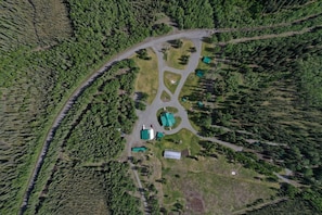 An aerial view of a property with a central building surrounded by forested areas and a winding road.