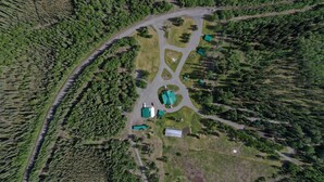 Une vue aérienne d’une propriété dont le bâtiment principal est entouré de zones boisées et auquel on accède par une route sinueuse.