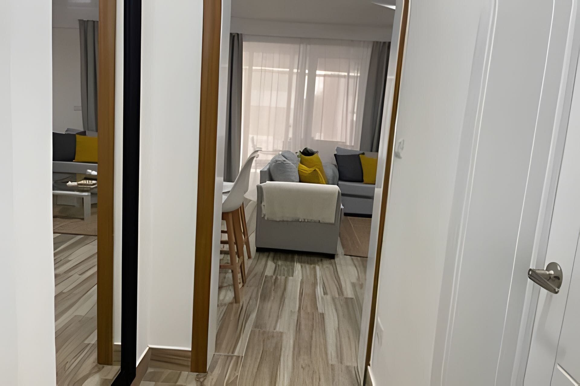Un pasillo que conduce a una sala de estar con un sofá, una mesa de centro y una silla.