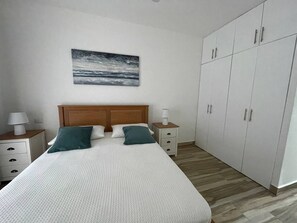 A bedroom with a bed, a nightstand, a lamp, a wardrobe, and a painting on the wall. - Sweet Home Bayahibe (Bayahíbe)
