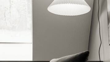 A room with a white paper cone pendant light, a gray sofa, and a large window with a view.