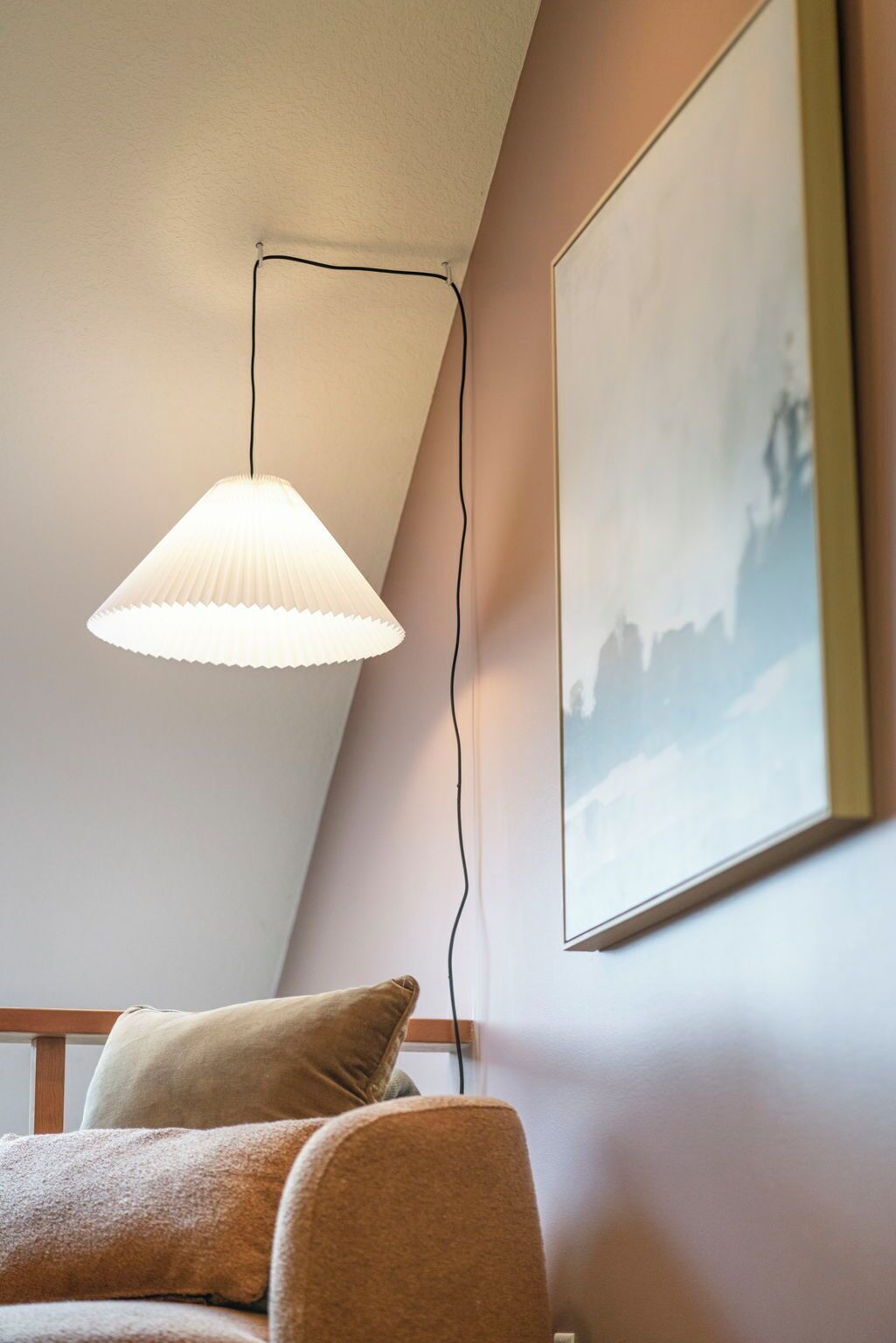 Habitació amb un llit individual, una làmpada penjant i un quadre al mur.