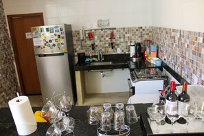 A kitchen with a refrigerator, coffee maker, and wine bottles.