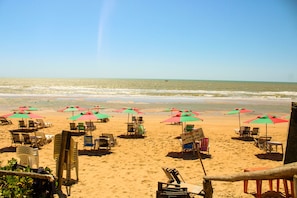 Una platja amb files de gandules i ombrel·les, un senyal i vista a l'oceà.