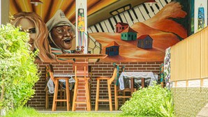 Une fresque représentant des maisons et un piano, ainsi que des meubles en bois et des lampes suspendues.