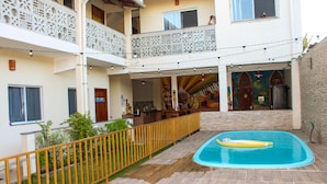 Une cour avec une piscine, une terrasse en bois et un espace délimité par une clôture.