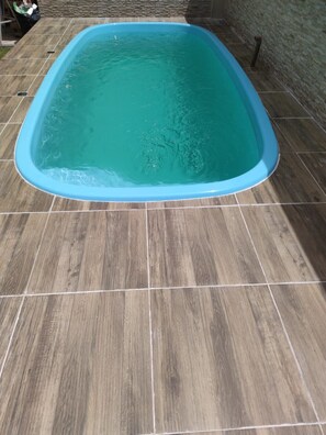 A swimming pool with a blue interior, surrounded by wooden deck tiles.