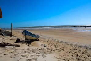 Ein Strand mit einem Boot, sandigem Ufer und blauem Himmel.