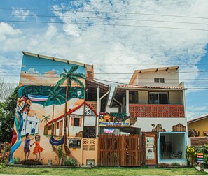 A building with a mural, a sign for 'Pousada Sonho Meu,' and a gated entrance.