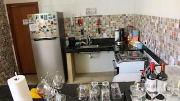 Cozinha com geladeira, cafeteira e garrafas de vinho.
