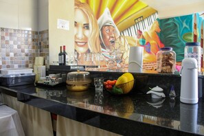 A kitchen counter with various items including a fruit bowl, wine bottles, glasses, and a coffee maker.