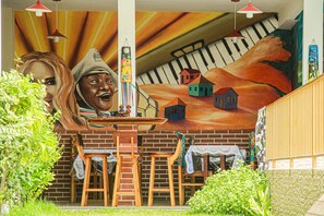 A mural with houses and a piano, wooden furniture, and hanging lights.