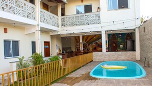A courtyard with a swimming pool, a wooden deck, and a fenced area. - Pousada Sonho Meu em Itaúnas - Quadruple Suite - QQP (Itaúnas)