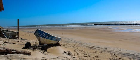 A beach with a boat, sandy shore, and clear sky.