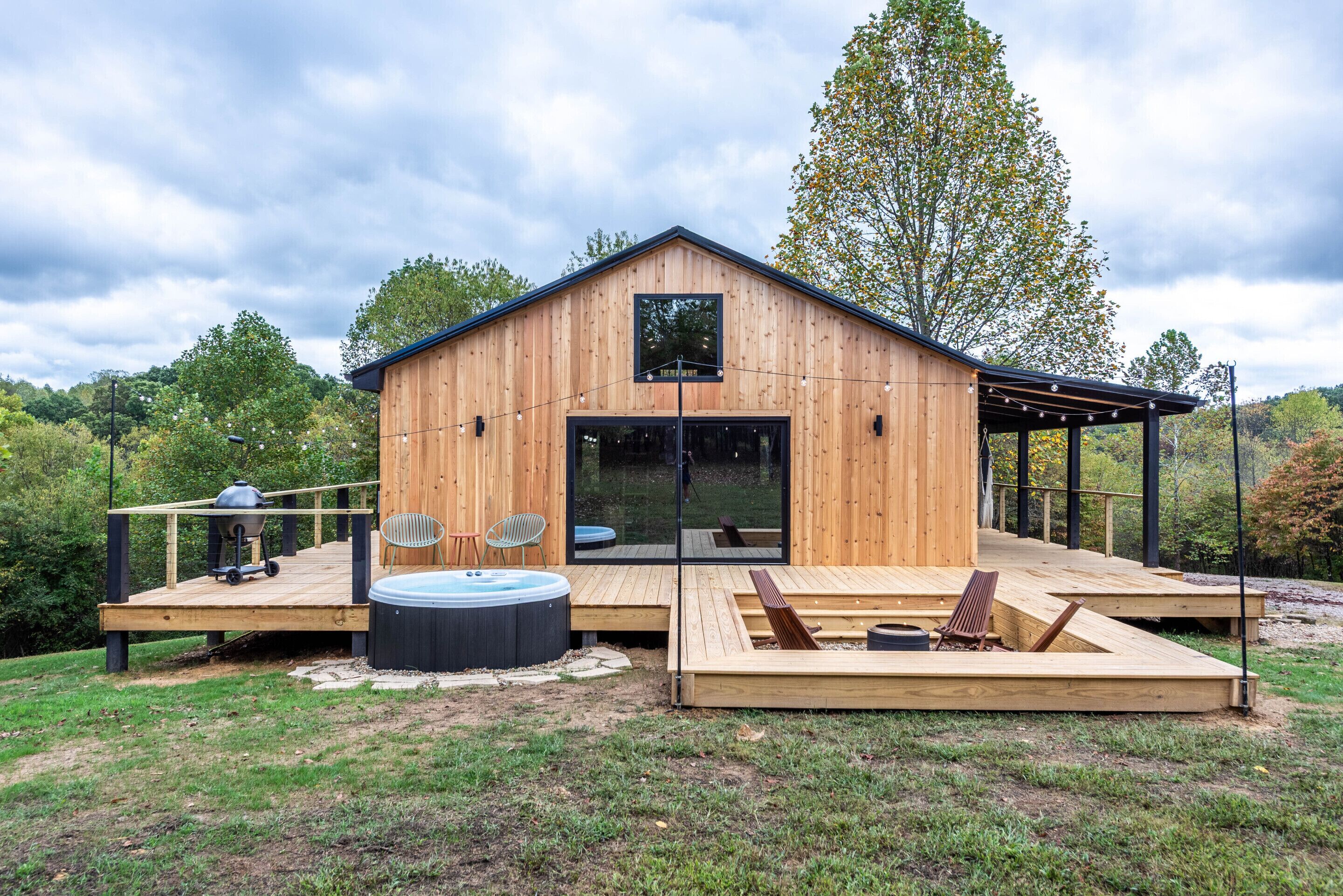 Eine Holzhütte mit Terrasse, Whirlpool und Sitzbereich im Freien.