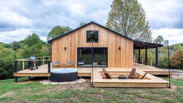 Eine Holzhütte mit Terrasse, Whirlpool und Sitzbereich im Freien.