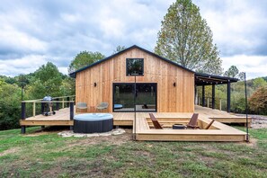 Una cabaña de madera con terraza, jacuzzi y zona de estar al aire libre.