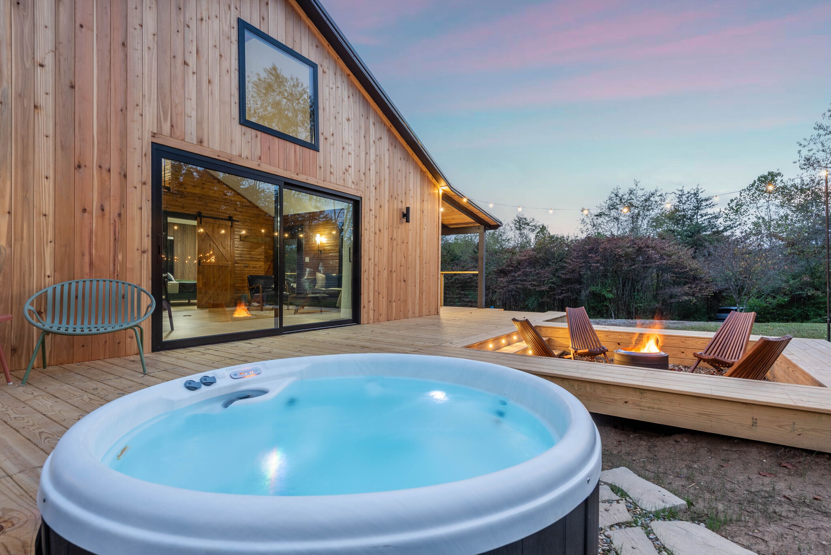 A wooden house with a hot tub, outdoor seating, and a fire pit.