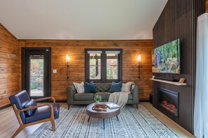 Una habitación acogedora con detalles de madera, un sofá, una silla, una chimenea y un televisor.