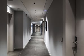 A modern hotel corridor with a long, straight path, recessed lighting, and a door with a keypad lock. - CO99 - COMFORT ROOM (Milano)